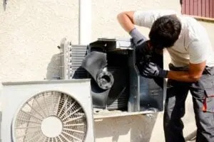 A man working on an air conditioner outside.